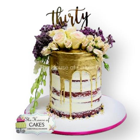 Dripping naked cake with flowers and topper