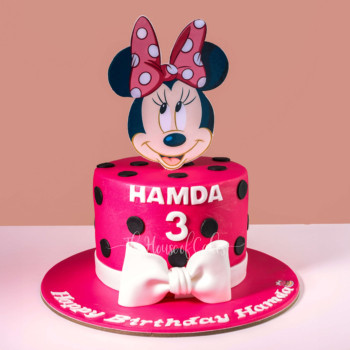 a pink birthday cake with a cartoon character on top