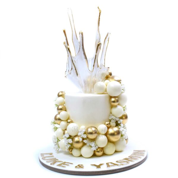 Cake with white and gold balls and sail on top