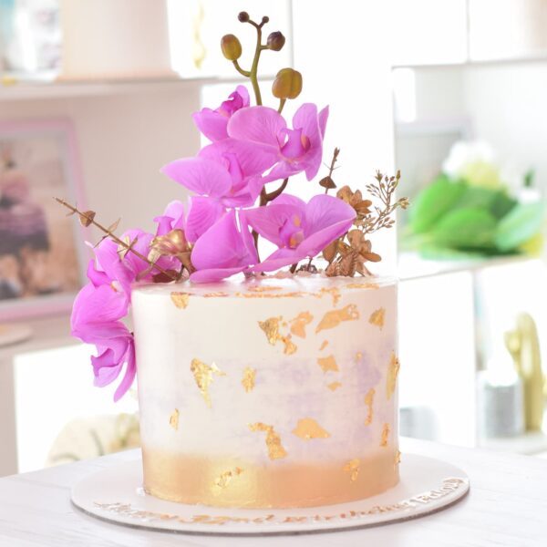 Cake with gold accents and pink orchids